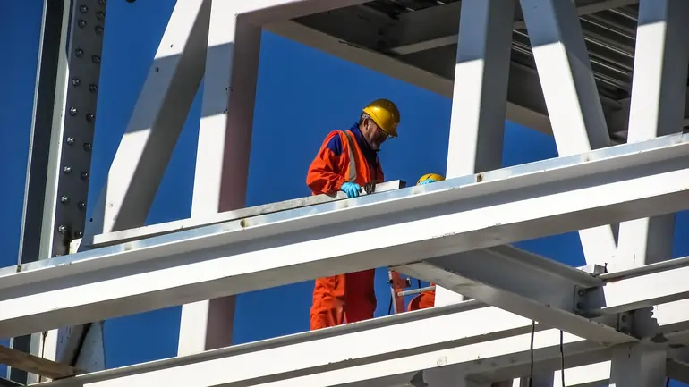 Operai che lavorano su delle travi d'acciaio in un cantiere edile | SOAsemplice