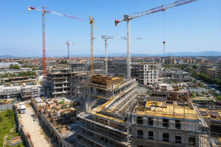 Grande cantiere residenziale con più gru e palazzine in costruzione per un programma del Piano casa 2026 | SOAsemplice