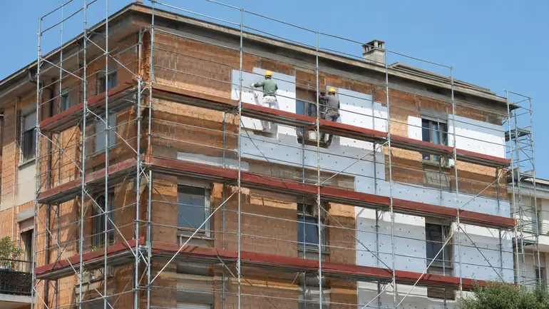 Cantiere di ristrutturazione di un condominio per il Superbonus 110%, con ponteggi e cappotto termico applicato sulla facciata | SOAsemplice