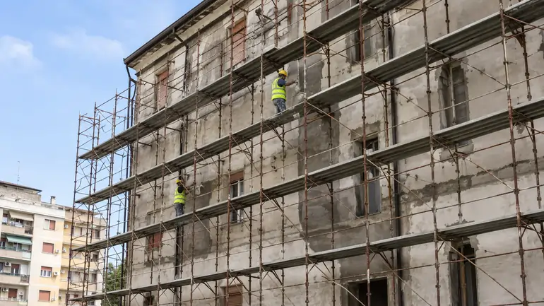 Cantiere di ristrutturazione di un edificio di edilizia residenziale pubblica con ponteggi e operai al lavoro | SOAsemplice